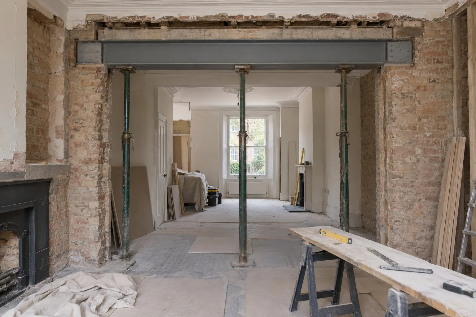 New steel beam spanning a removed wall between two reception rooms of a Victorian terraced house, with temporary props in place